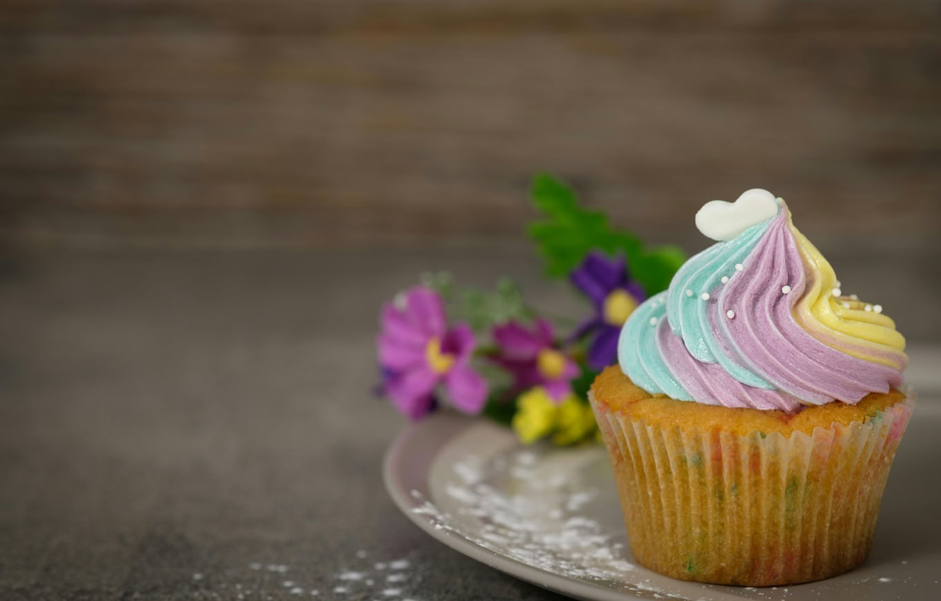 A pastel frosted cupcake with flowers on a plate, perfect for desserts and celebrations.